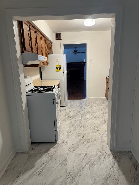 3405 Cherrywood Road Austin, TX 78722 - Photo 5 of 17 Kitchen with gas range gas stove, brown cabinets, under cabinet range hood, light countertops, and light marble finish floors