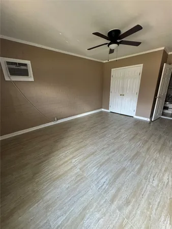 an empty room with wooden floor ceiling fan and windows