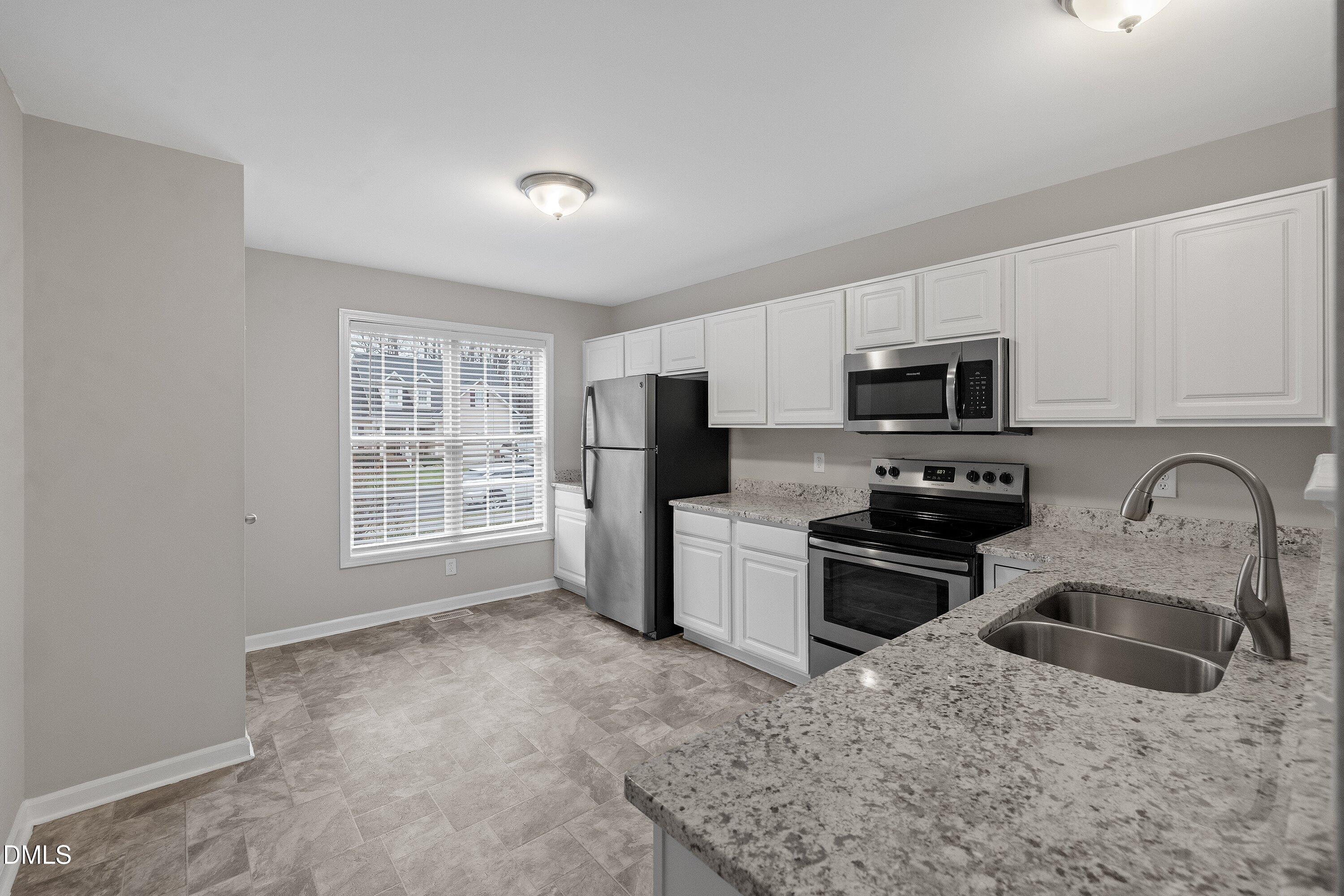 140 Melksham Road Wake Forest, NC 27587 - Photo 17 of 34 a kitchen with stainless steel appliances granite countertop a stove top oven a sink dishwasher a refrigerator and cabinets with wooden floor