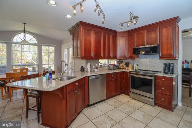 a kitchen with stainless steel appliances granite countertop a stove top oven a sink a dining table and chairs
