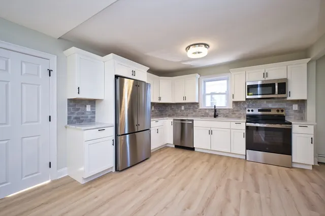 a kitchen with a refrigerator stove and white cabinets