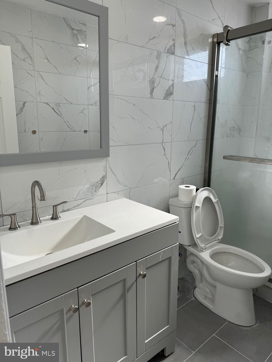 139 Rosemar Street Philadelphia, PA 19120 - Photo 12 of 19 a bathroom with a granite countertop toilet sink and mirror