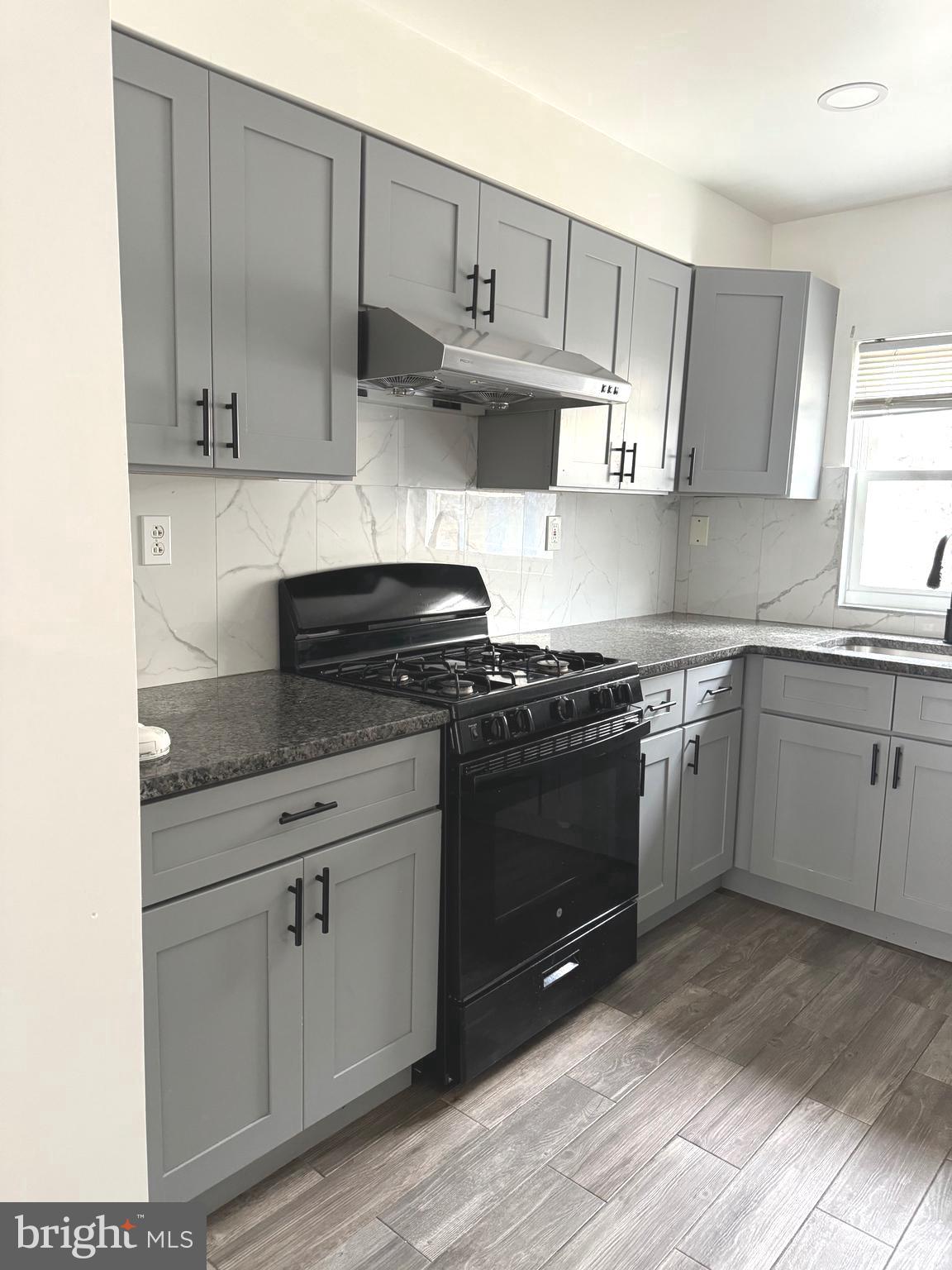 139 Rosemar Street Philadelphia, PA 19120 - Photo 5 of 19 a kitchen with granite countertop a stove a sink and cabinets