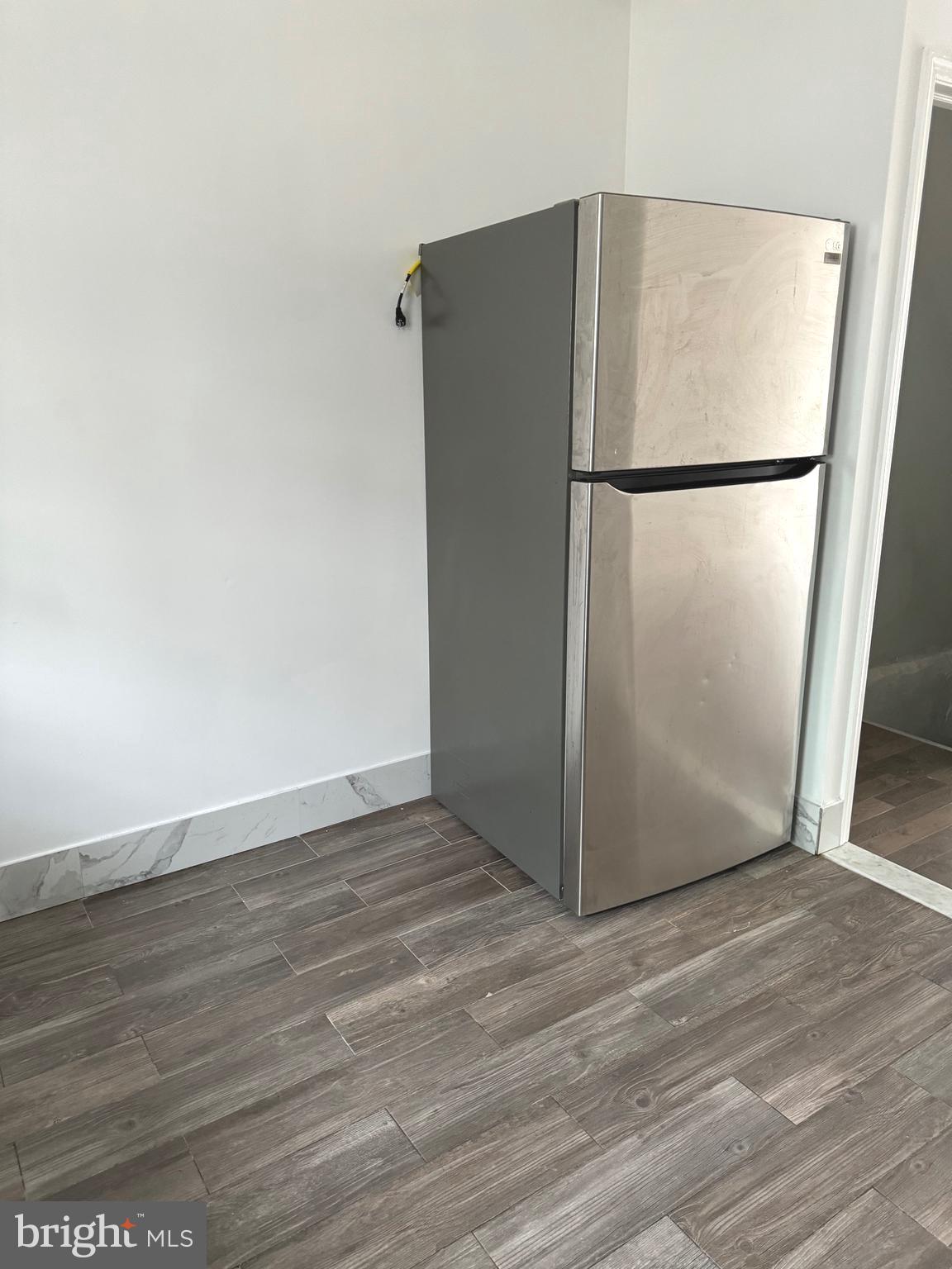 139 Rosemar Street Philadelphia, PA 19120 - Photo 7 of 19 a view of a refrigerator in kitchen and an empty room with wooden floor