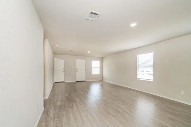 an empty room with wooden floor and window