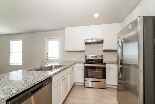 a kitchen with stainless steel appliances granite countertop a sink stove and refrigerator