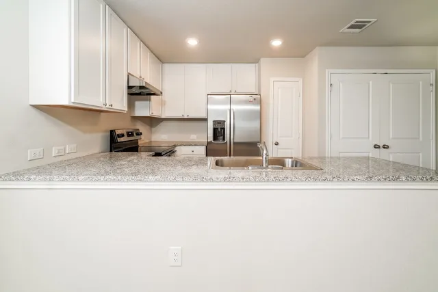 a kitchen with stainless steel appliances granite countertop a sink refrigerator and cabinets
