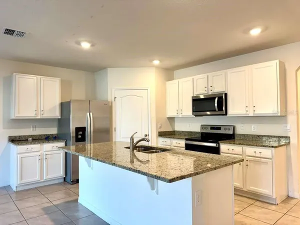 a kitchen with granite countertop a sink stainless steel appliances and white cabinets