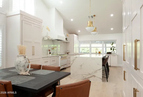 a large kitchen with granite countertop a table chairs in it and wooden floors