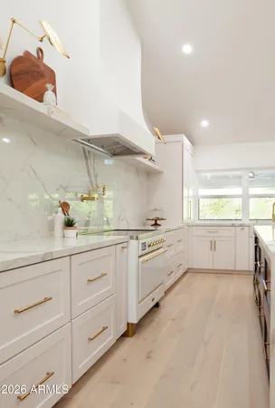 a large white kitchen with granite countertop a sink white cabinets and stainless steel appliances