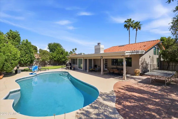 a view of a swimming pool with lawn chairs and plants