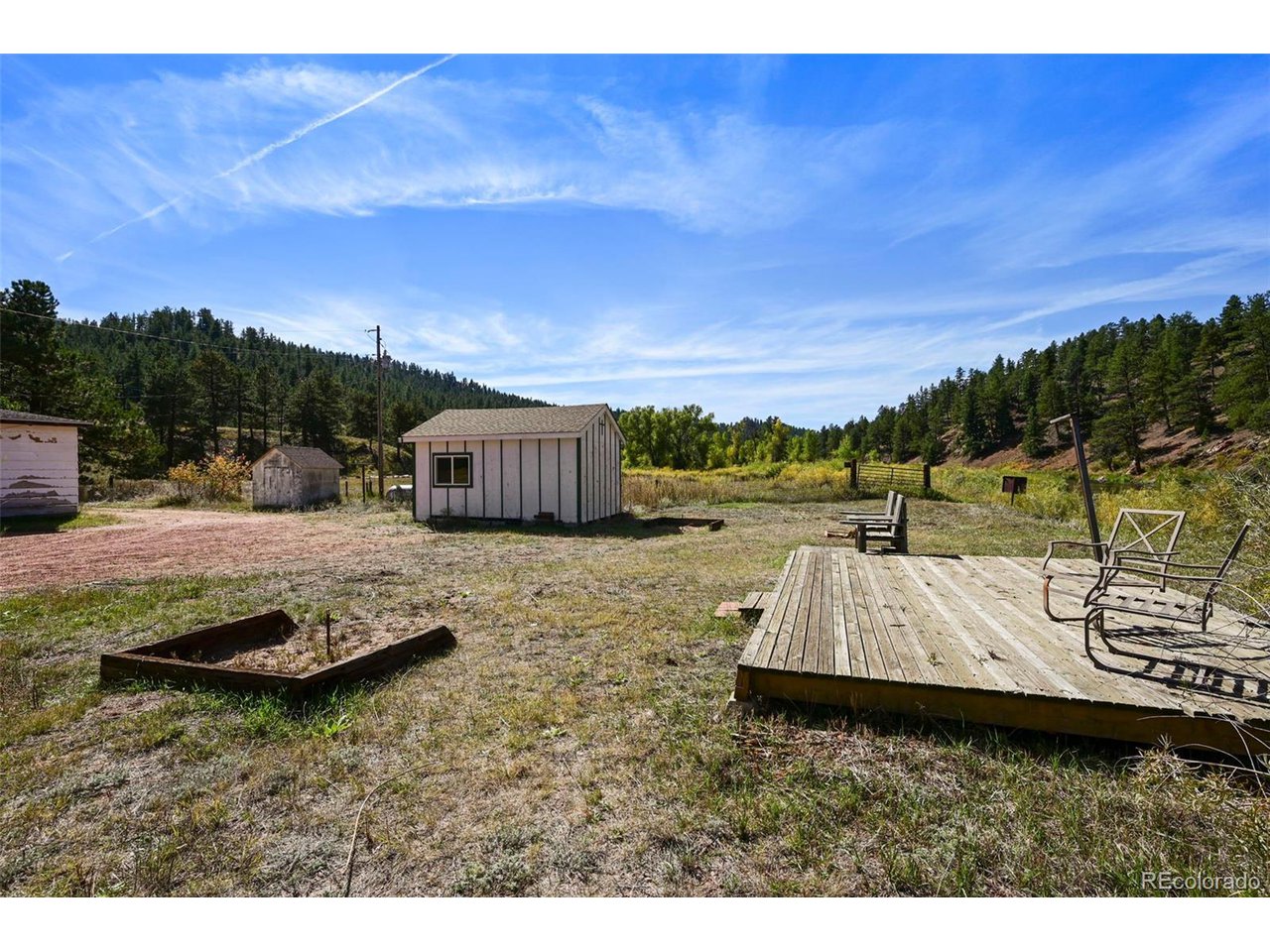 2677 South Platte River Road Sedalia, CO 80135 - Photo 22 of 42 a view of a backyard with lawn chairs and wooden fence