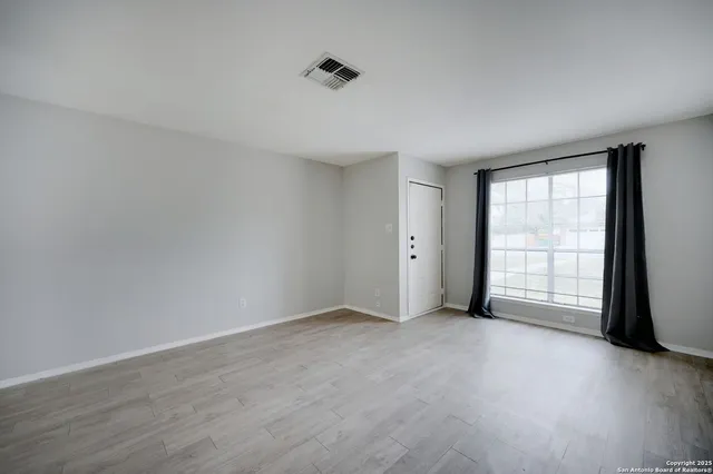 an empty room with wooden floor and windows