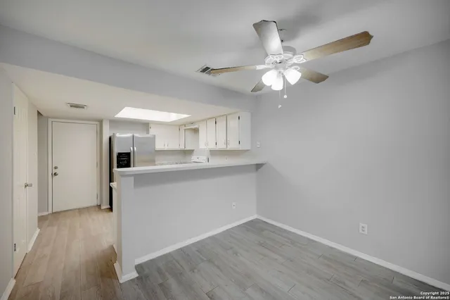 a room with kitchen island a ceiling fan and wooden floor