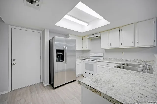 a kitchen with granite countertop a refrigerator and a sink