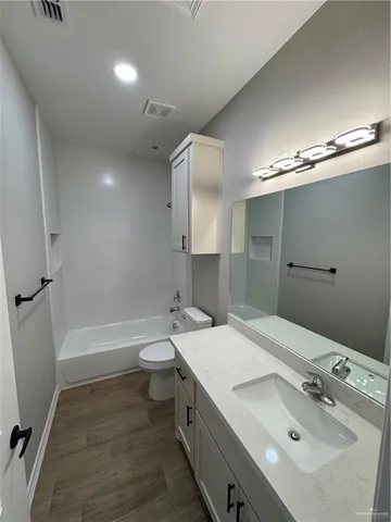 a view of a hallway with wooden floor and a ceiling fan