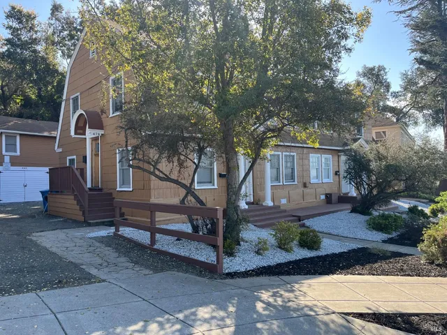 a view of a house with a tree in front of it