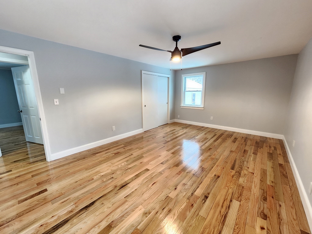 405 Queen Lake Road Phillipston, MA 01331 - Photo 14 of 25 an empty room with wooden floor and windows