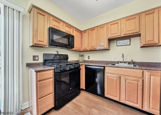 a kitchen with granite countertop wooden cabinets stainless steel appliances and a sink