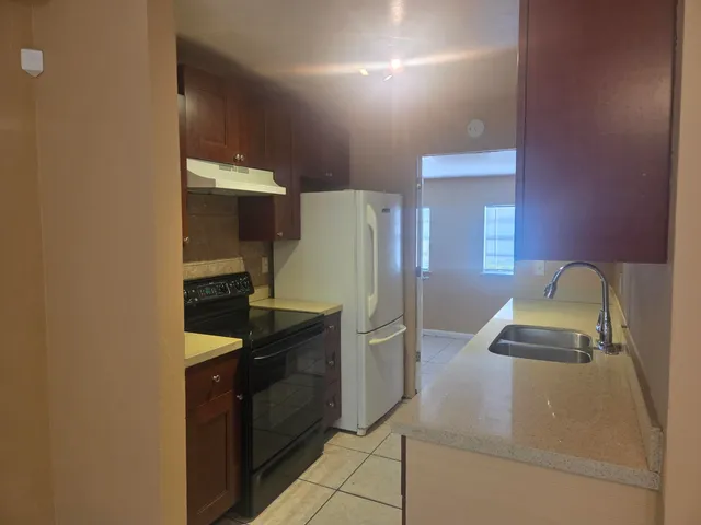 a kitchen with granite countertop a refrigerator and a sink
