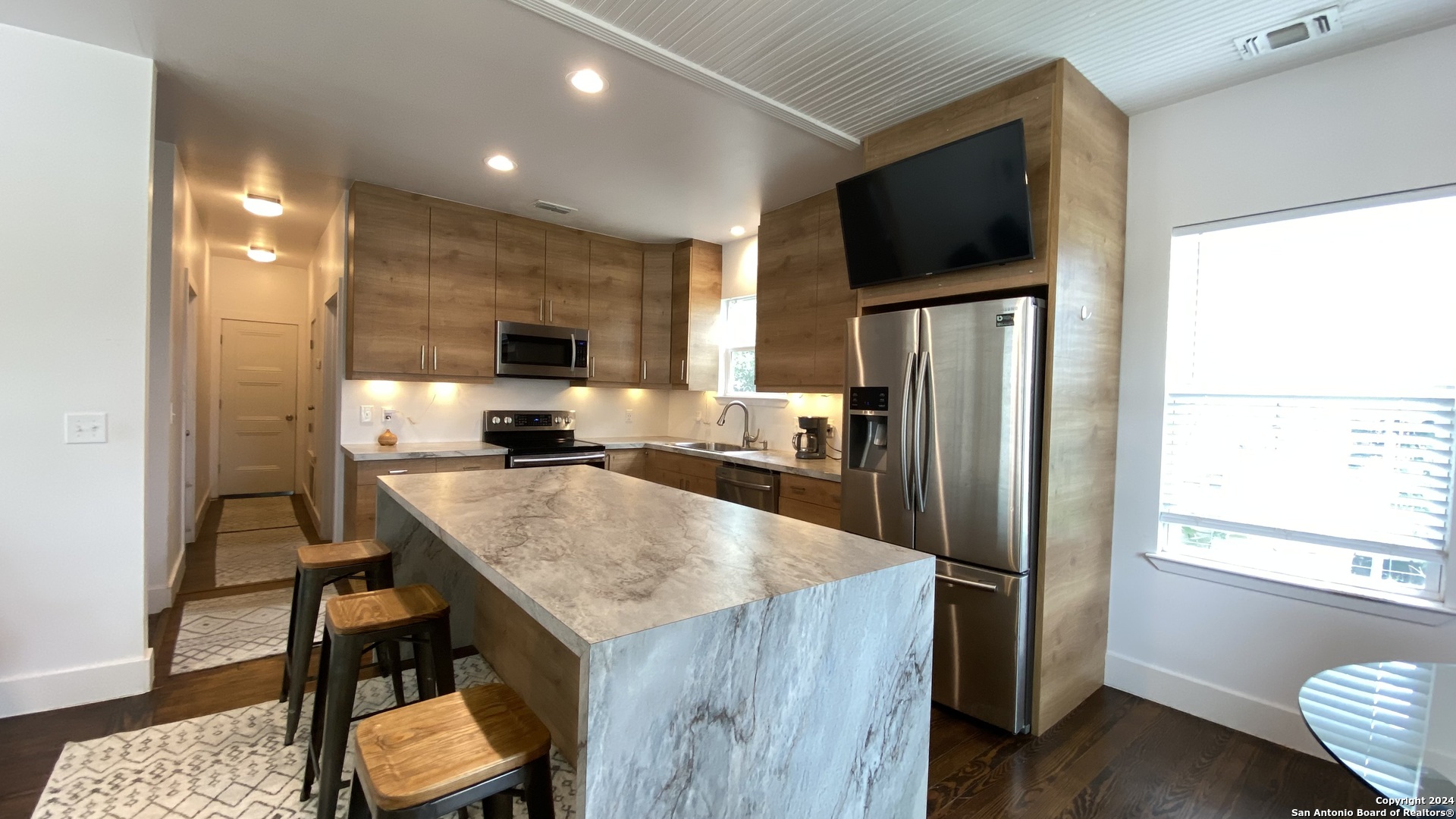 a kitchen with kitchen island a counter top space appliances and a refrigerator