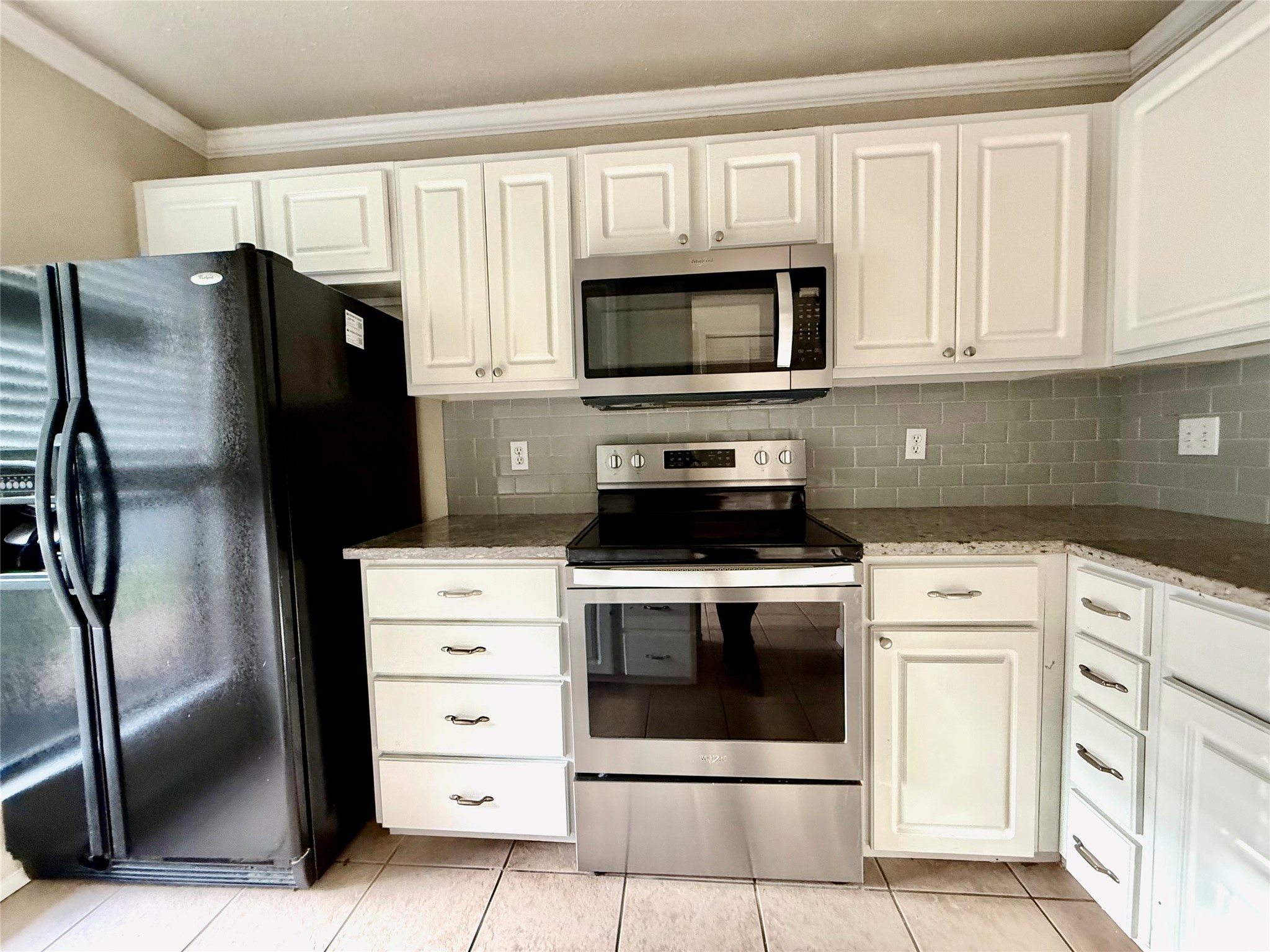 2018 West Rundberg Lane, Unit 6A Austin, TX 78758 - Photo 5 of 16 Kitchen with stainless steel appliances, white cabinetry, decorative backsplash, crown molding, and dark stone counters