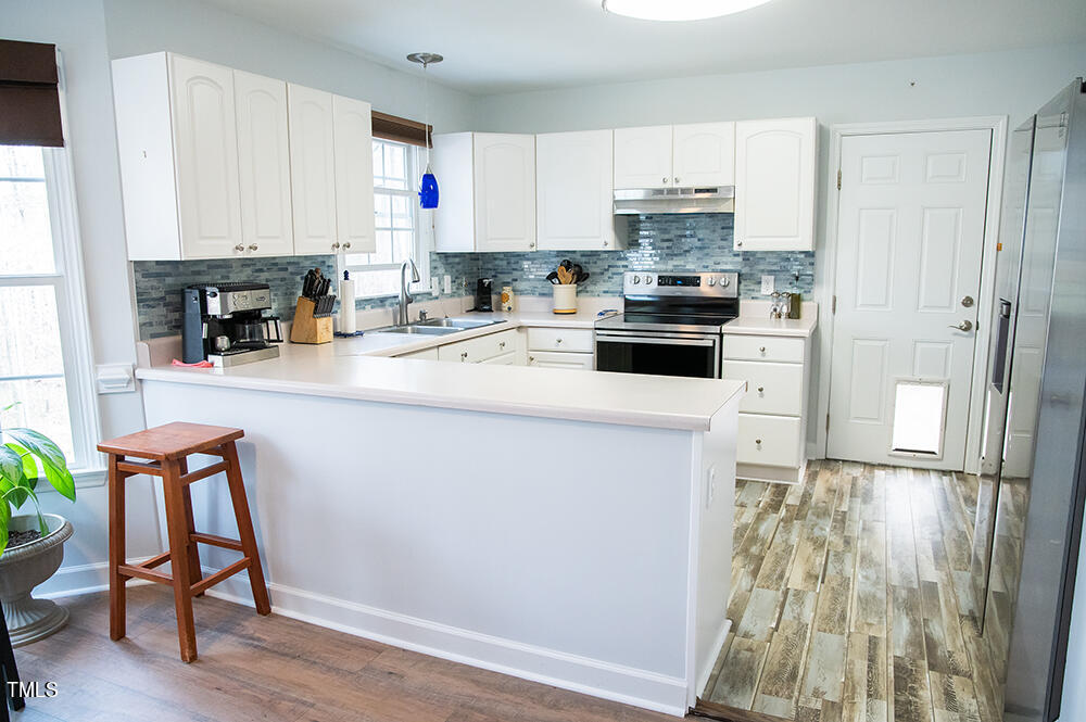 46 Beaver Crossing Road Roxboro, NC 27574 - Photo 12 of 50 a kitchen with granite countertop wooden floors and white stainless steel appliances