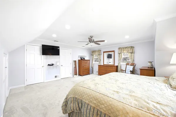 a large bedroom with a bed and a flat screen tv