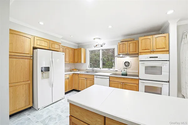 a kitchen with stainless steel appliances granite countertop a refrigerator a stove and a sink with large window