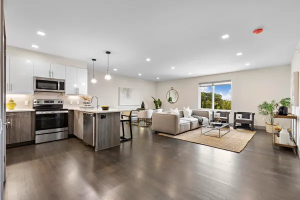 a living room with furniture kitchen view and a wooden floor