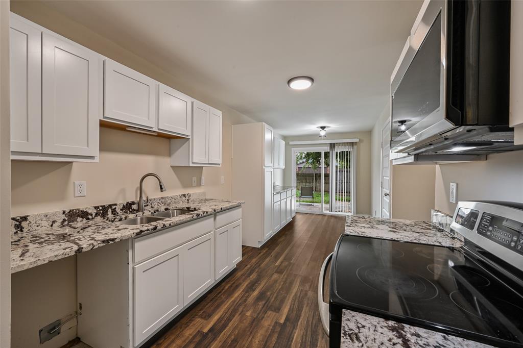 7318 Emory Oak Lane Dallas, TX 75249 - Photo 13 of 28 Kitchen featuring white shaker cabinetry, granite countertops, stainless steel appliances, wood-finish flooring, and a sliding glass door leading to an outdoor area