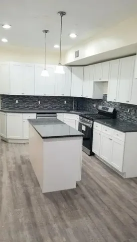 a large kitchen with stainless steel appliances granite countertop a stove a sink dishwasher and a refrigerator