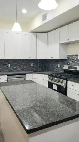 a kitchen with stainless steel appliances granite countertop a sink a stove and a counter top space