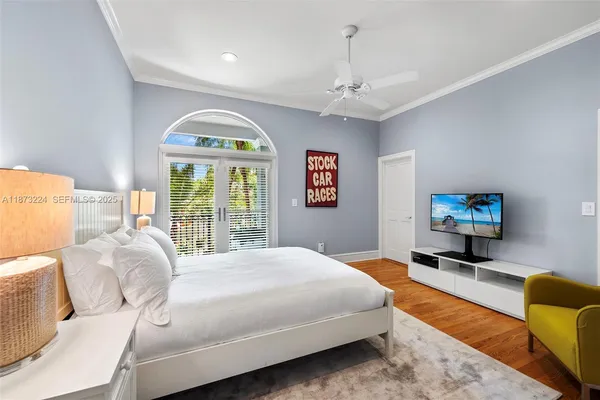 a spacious bedroom with a bed a couch and a flat tv screen on dresser