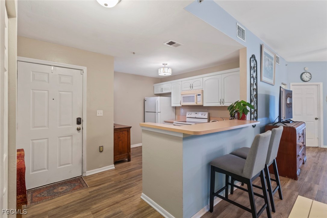 15430 Bellamar Circle, Unit 3014 Fort Myers, FL 33908 - Photo 6 of 20 a kitchen with kitchen island a dining table chairs cabinets and wooden floor