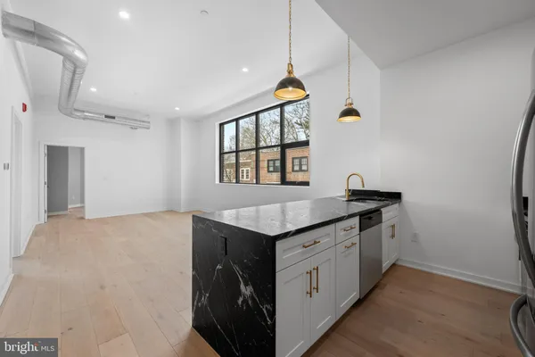 a kitchen with stainless steel appliances granite countertop a sink and a stove with wooden floor