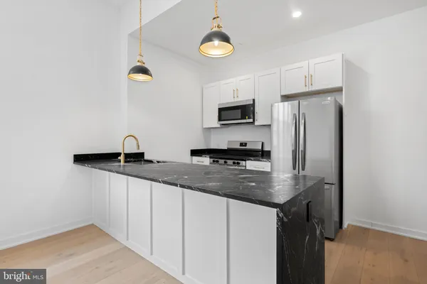 a kitchen with stainless steel appliances granite countertop a sink a stove and refrigerator