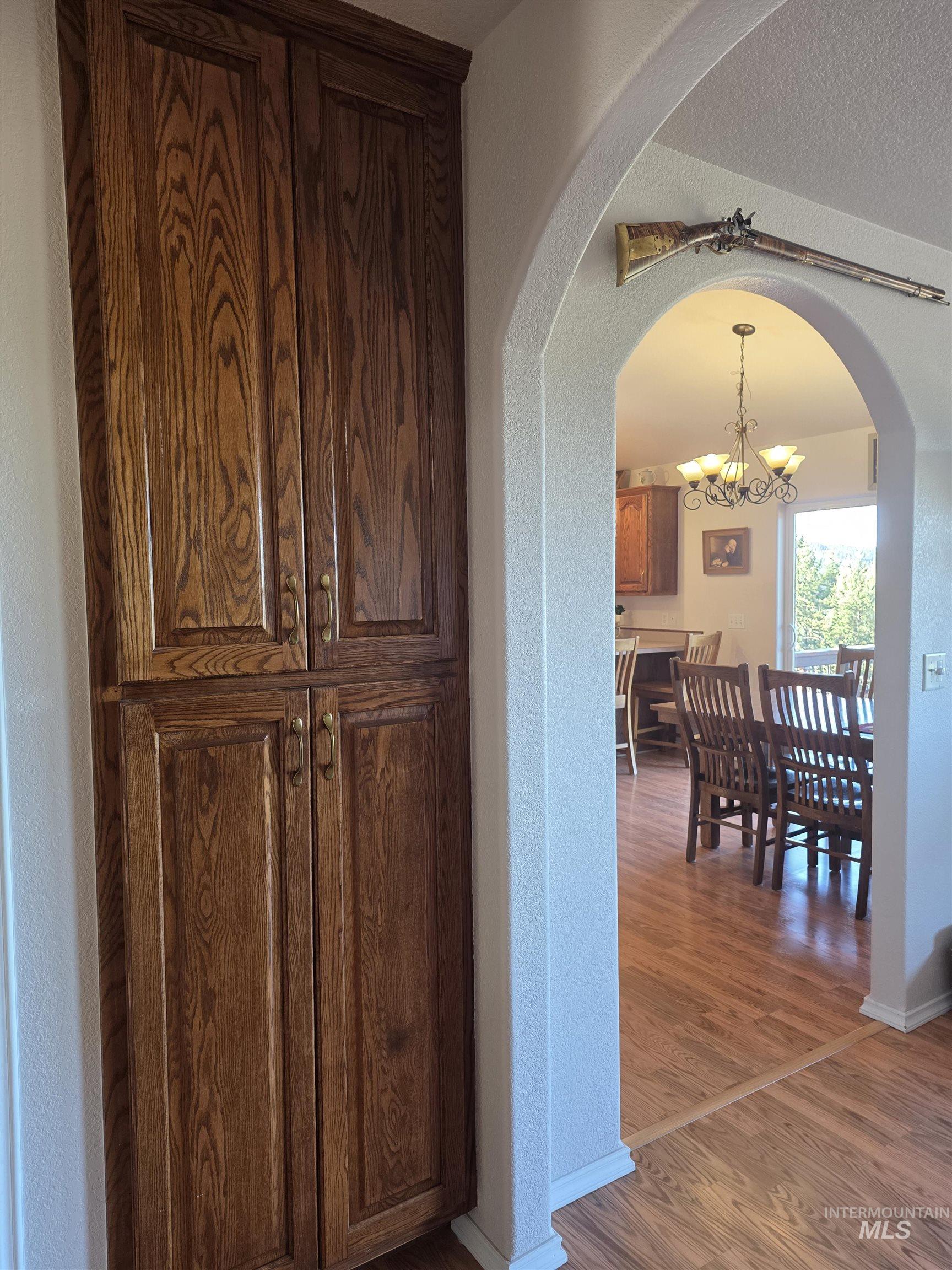 5288 Lakeview Road Orofino, ID 83544 - Photo 26 of 36 Hall with hanging lights, a textured wall, arched walkways, wood finished floors, and a textured ceiling