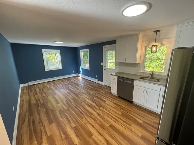 a kitchen with granite countertop a sink cabinets wooden floor and stainless steel appliances