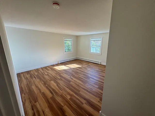a view of an empty room with a window and wooden floor
