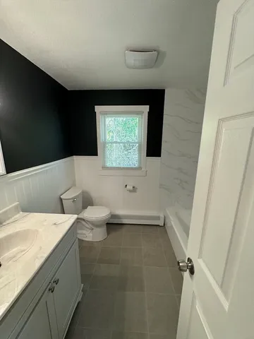 a bathroom with a granite countertop sink a toilet and a bathtub