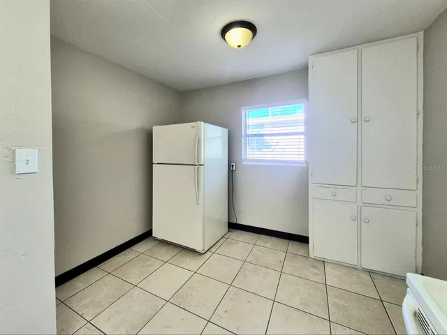 a view of kitchen with white cabinets and a refrigerator
