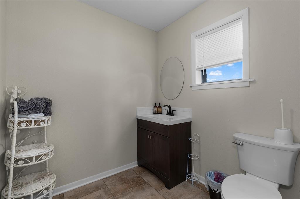 1131 Speights Road Keatchie, LA 71046 - Photo 17 of 33 Window with blinds, oval mirror, single vanity with dark wood-finish cabinetry, white countertop, and tile flooring