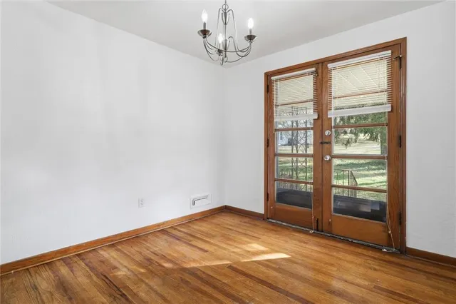 a view of an empty room with wooden floor and a ceiling fan