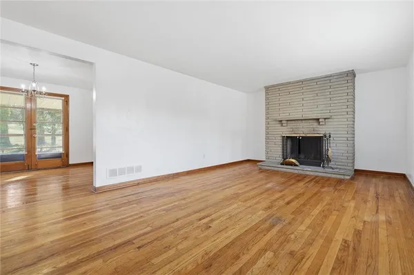 an empty room with wooden floor fireplace and windows
