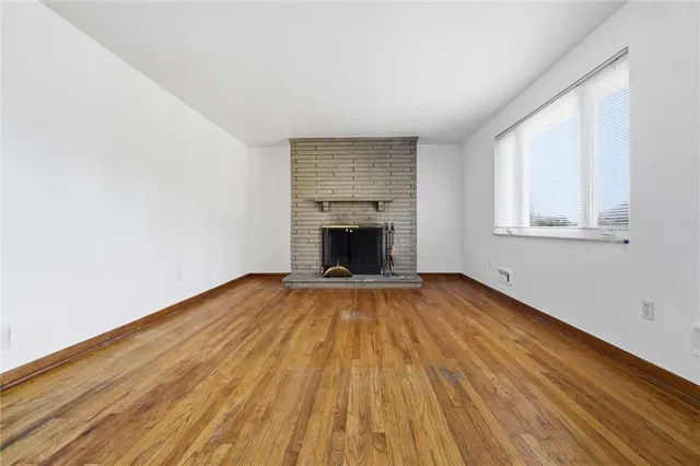 an empty room with wooden floor and a fireplace