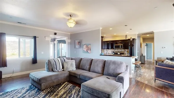 a living room with stainless steel appliances furniture a rug and a view of kitchen
