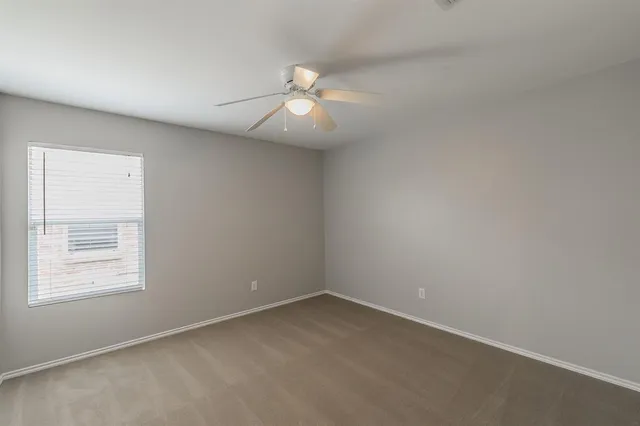 an empty room with a window and ceiling fan