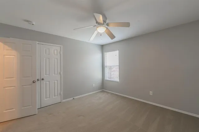 an empty room with windows and fan