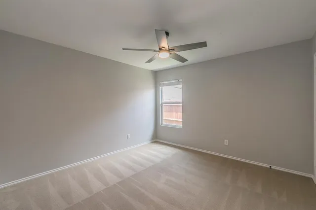 an empty room with a window and ceiling fan